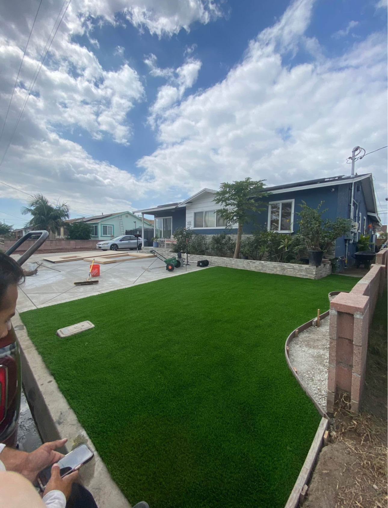 Finished front yard turf lawn with concrete patio and stone-veneer planter
