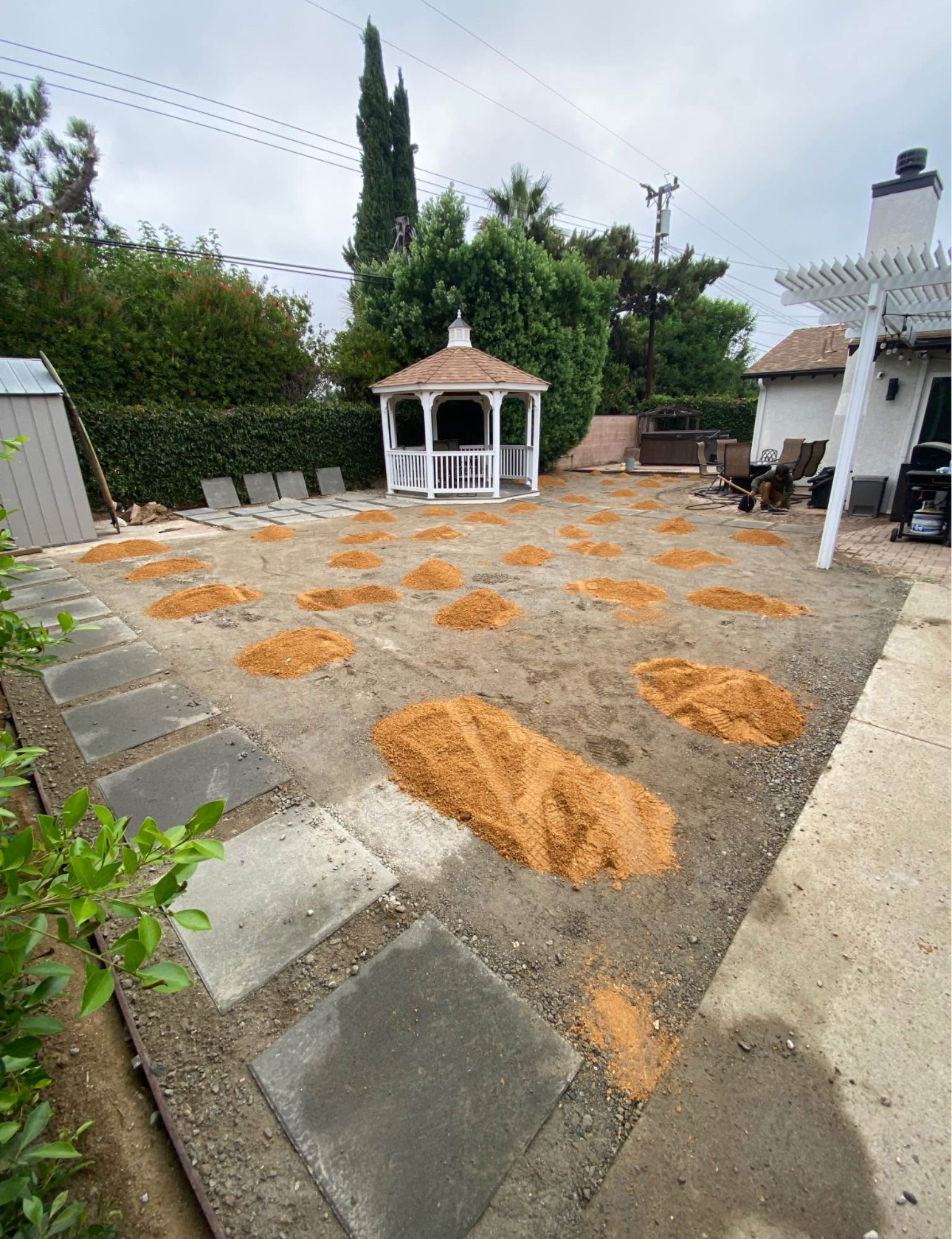 Old patio slab prepped with sand piles before turf install