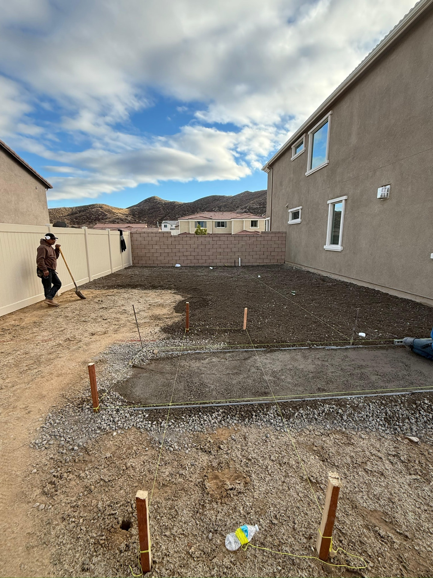 Graded dirt backyard staked out for a new paver patio