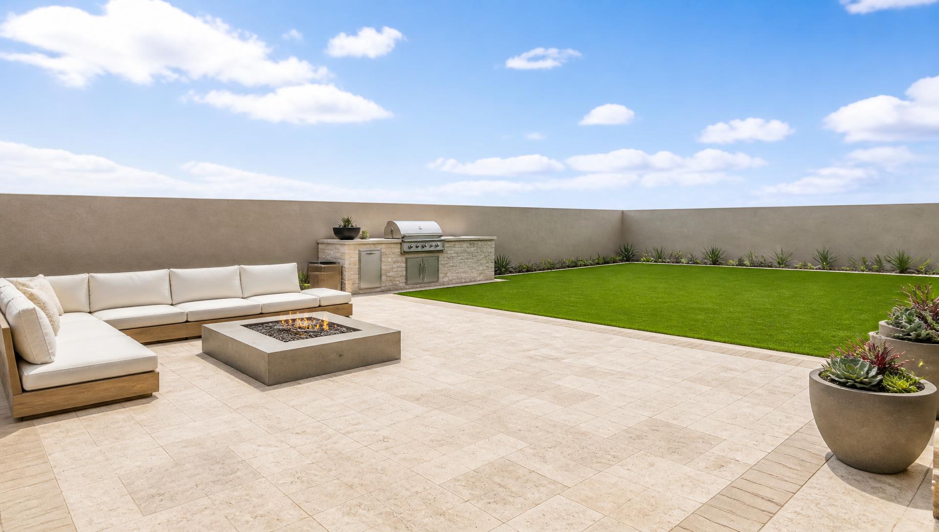 Remodeled Southern California backyard with travertine paver patio, outdoor sectional, fire table, built-in BBQ island and manicured lawn